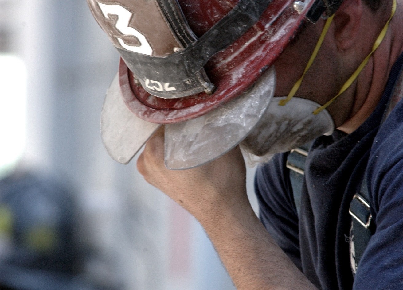 A firefighter rubs his eyes in tiredness or grief